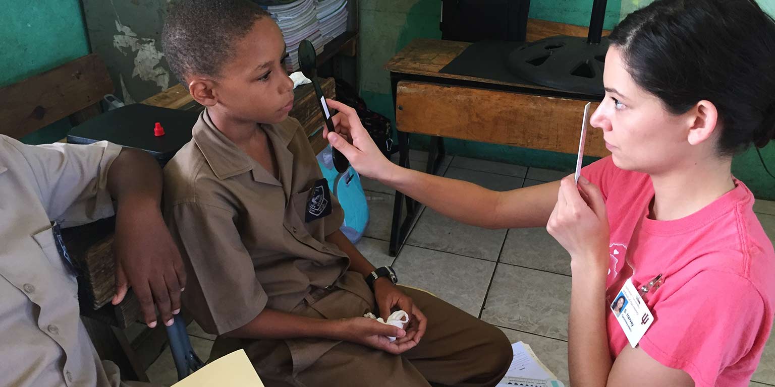A student volunteer performs an eye exam on a young boy in Frome, Jamaica.