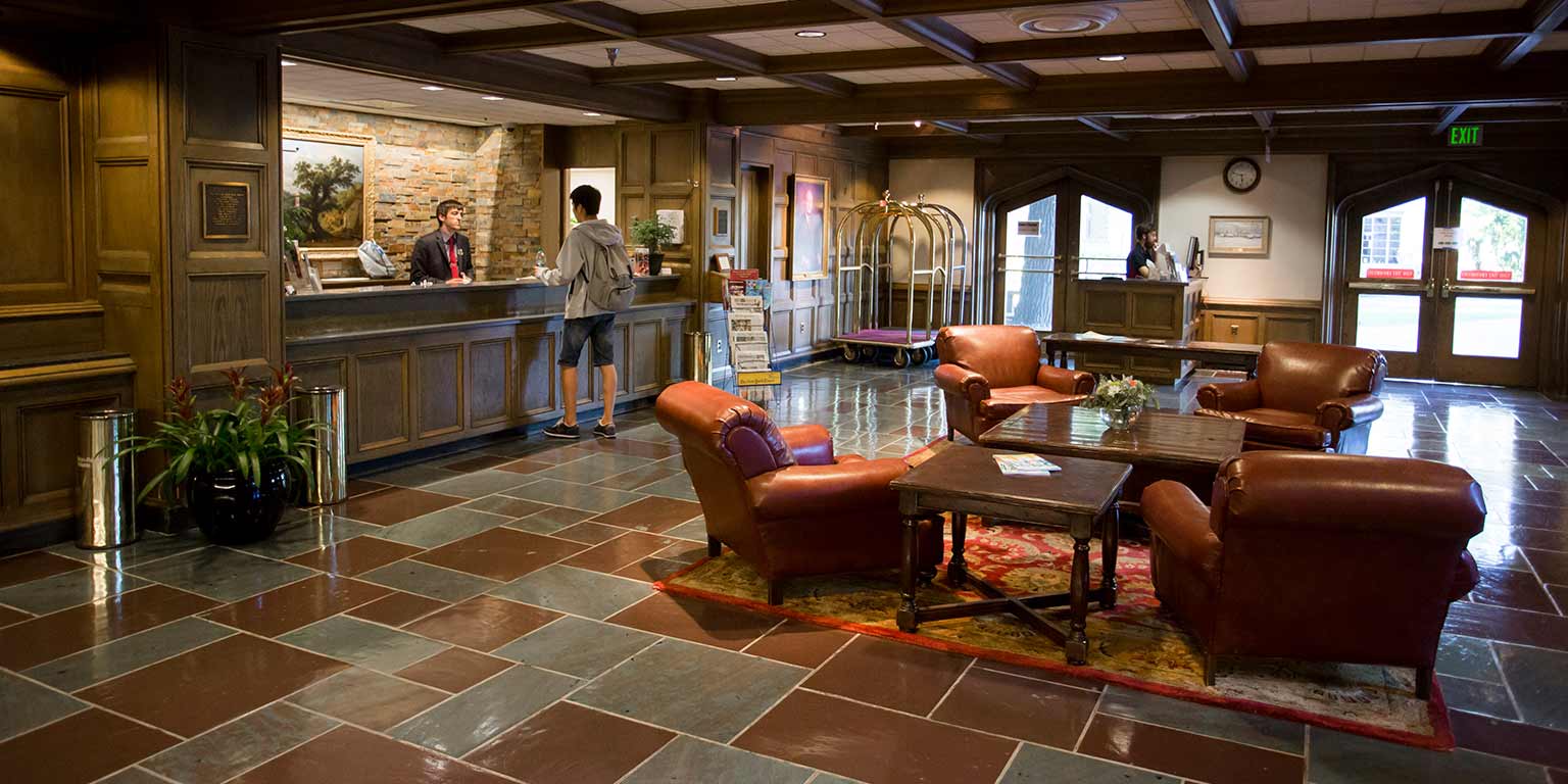 The front lobby of the Biddle Hotel has a seating area with four plush leather seats and a concierge desk.
