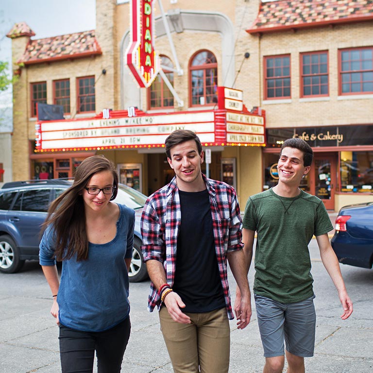 A group of three students walk from the Buskirk Chumley Theatre in downtown Bloomington.