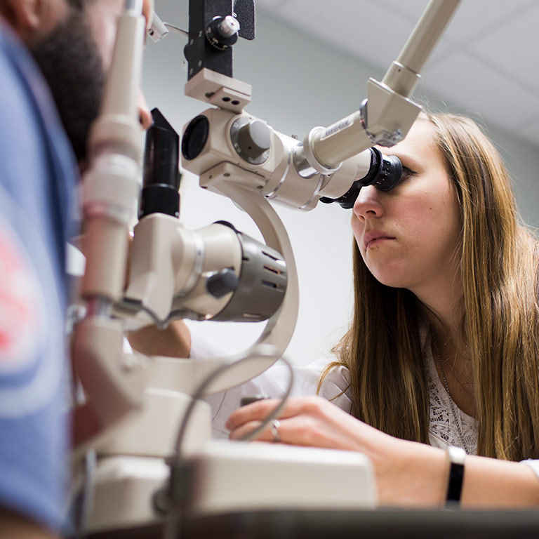 A female optometry student examines a patient's eyes.