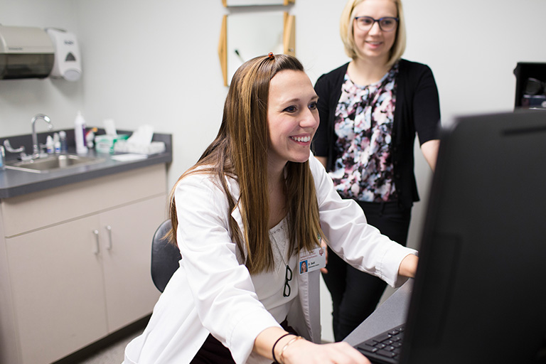 A smiling optometry student analyzes results from an eye exam