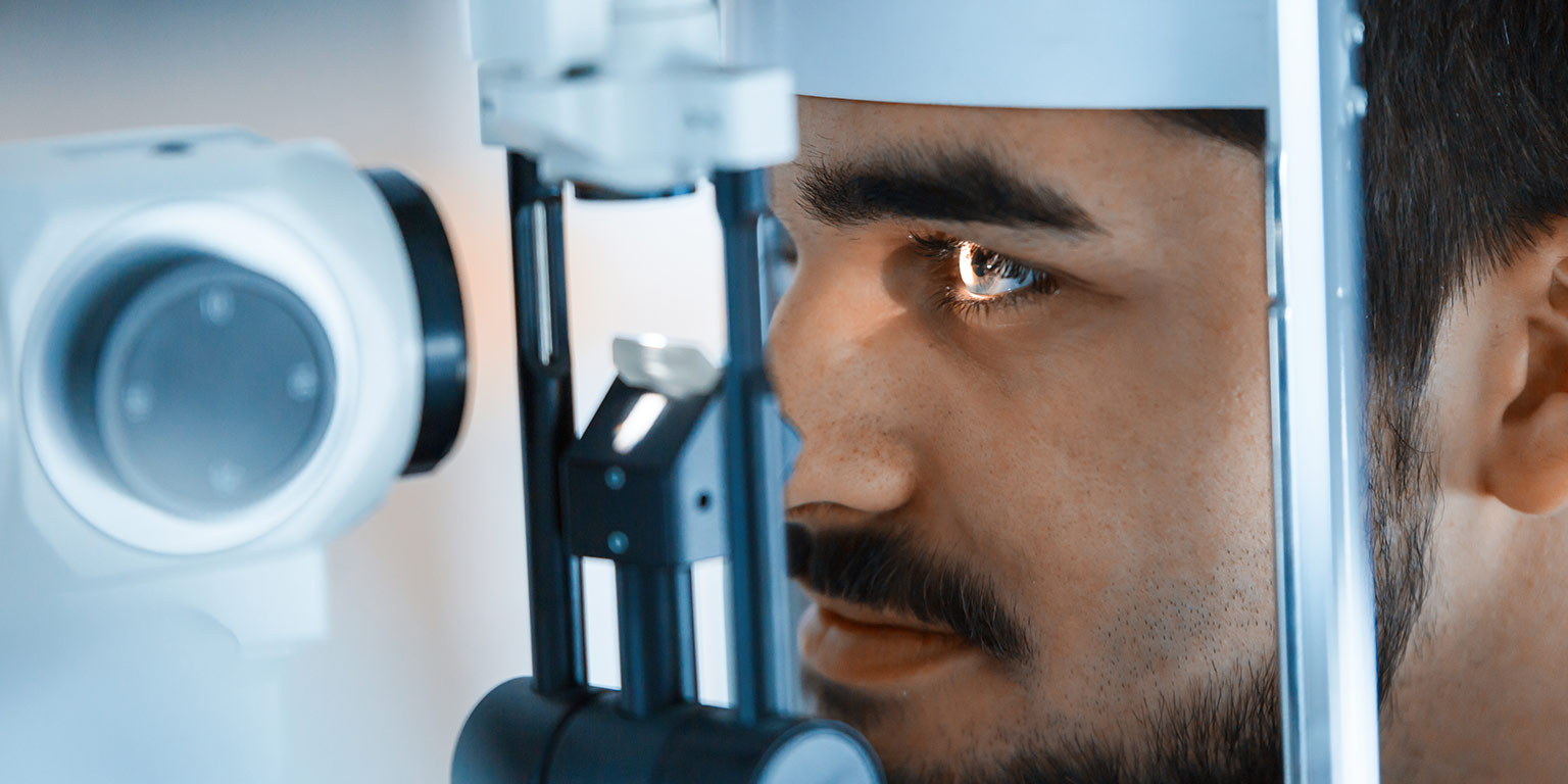 A male patient stares into the light of a slit lamp